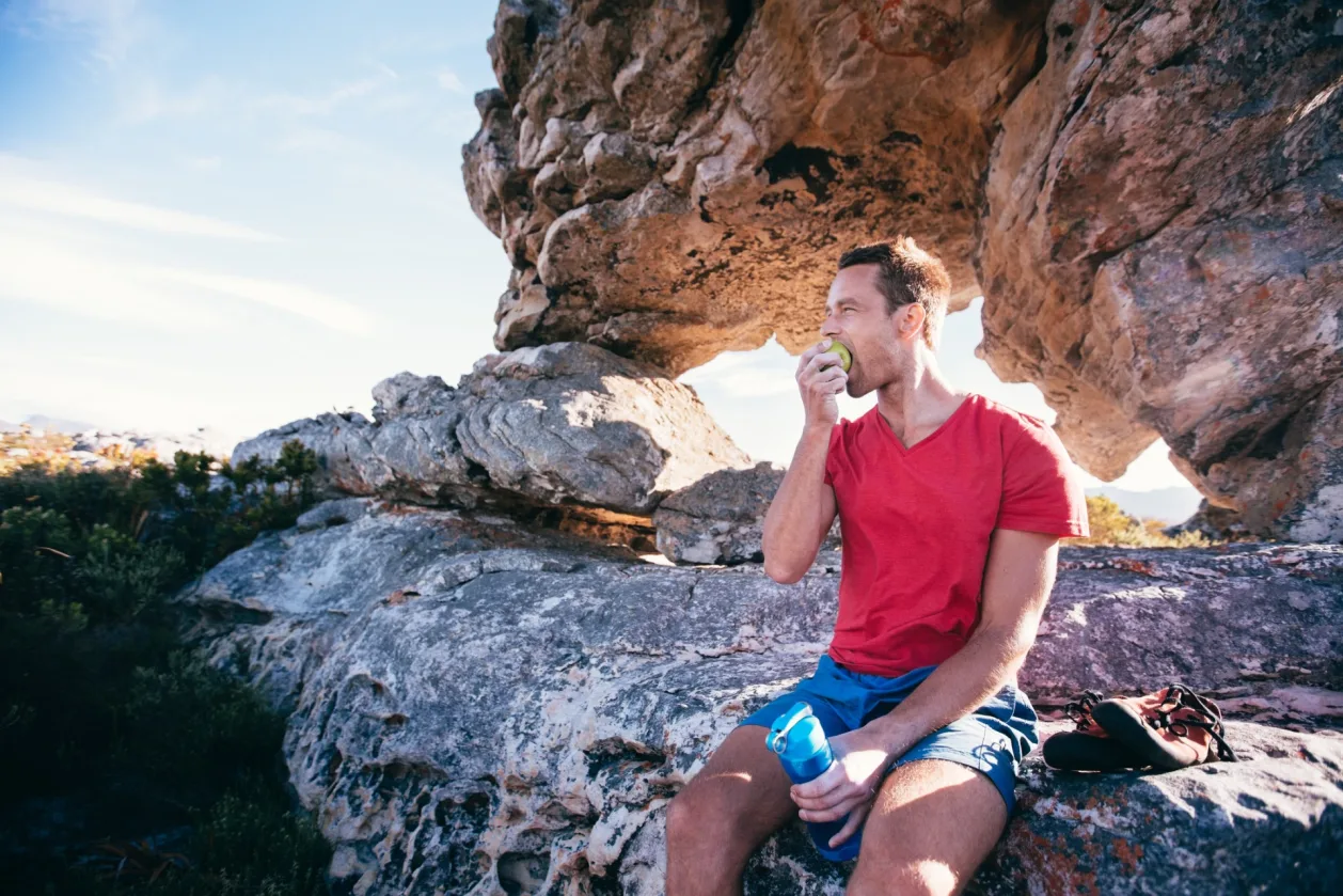climber man eating apple on mountain